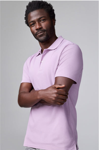 Man wearing a light purple polo shirt against a gray background