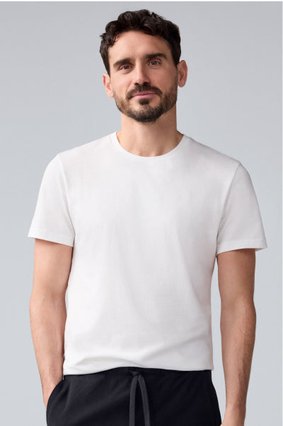 Man wearing a plain white t-shirt against a light gray background