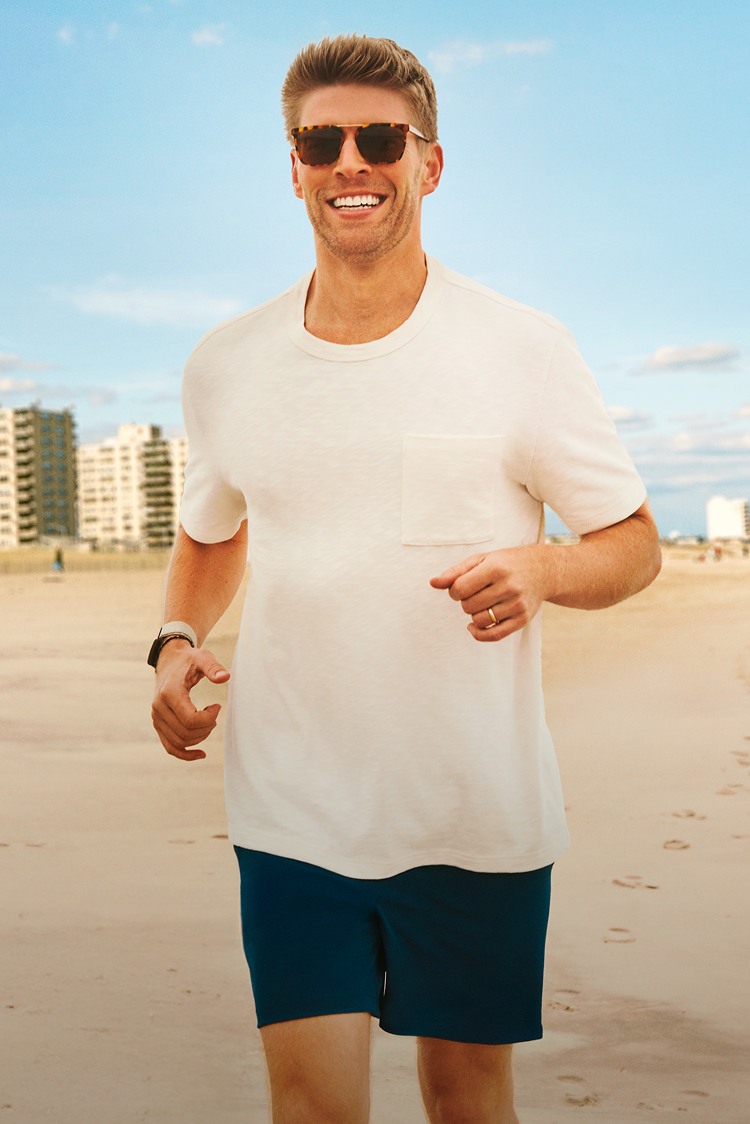 Man wearing sunglasses and a white t-shirt on a beach
